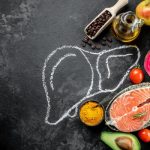 Home 4 A chalk drawing of a liver on a chalkboard, with various foods, spices, and oils arranged around it.